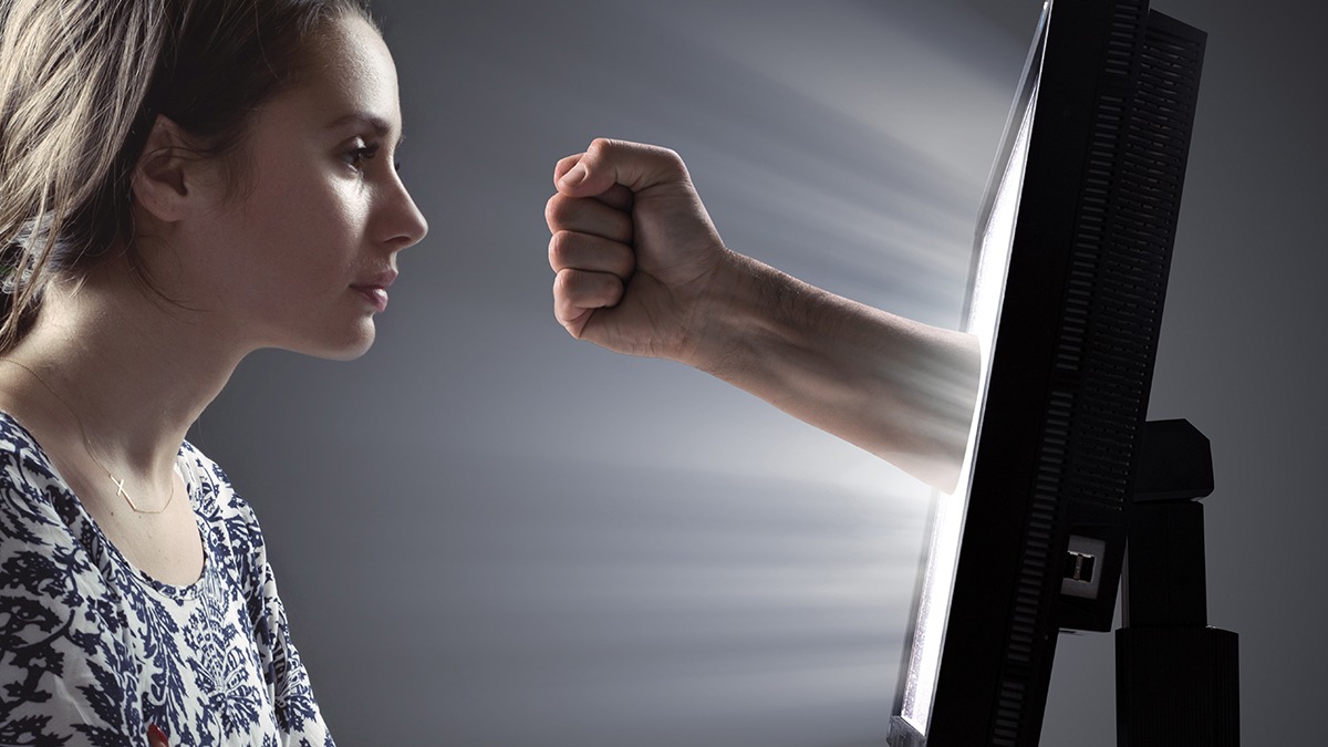 Man's fist punching out of a computer screen towards a woman's face